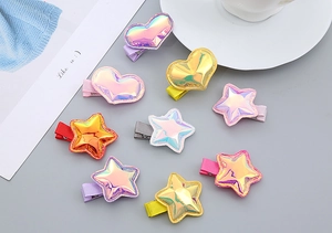Detailed view of colorful holographic star and heart hair clips on a soft grey surface