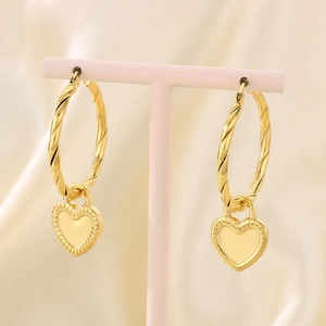 Close-up of golden hoop earrings with heart-shaped pendants and twisted rope texture design