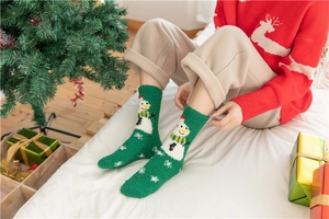 Detail of green coral fleece Christmas socks featuring snowman and snowflake patterns
