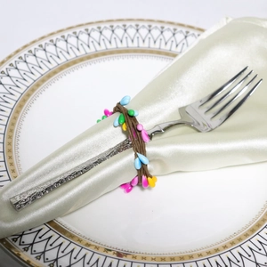 Detail of Easter napkin ring featuring colorful berries over a white satin napkin and plate