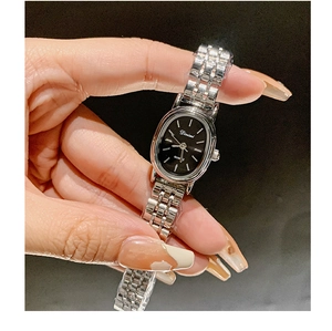 Detail of silver chain strap watch with black oval dial and minimalist quartz movement