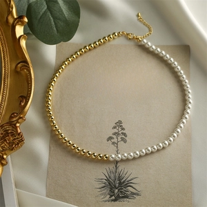 Detail of half gold bead and half white pearl necklace on vintage paper background