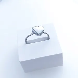 Minimalist stainless steel twisted rope ring with heart charm on a display stand