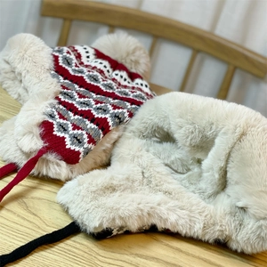 Detail of jacquard knit earflap hat with thick faux fur lining and braided chin straps