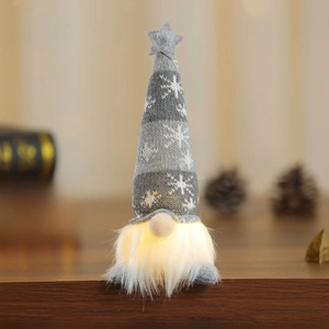 Detail of grey knitted Christmas gnome with LED glowing light and snowflake pattern hat