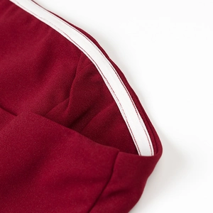 Close-up of wine red elegant dress showing white trim detail and fabric texture