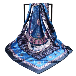 Detail of blue and pink paisley silk scarf with geometric patterns on a black display stand