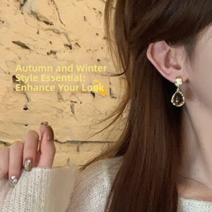 Detail of vintage gold hammered teardrop earrings with amber stone on model