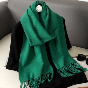 Close-up of green fringe scarf texture on black sweater with soft cashmere feel