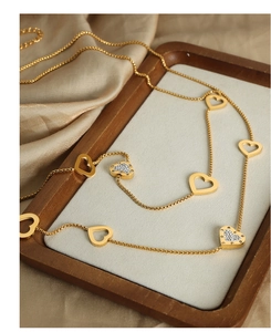 Detail of gold heart pendant necklace featuring hollow designs and zircon stone inlays