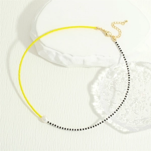 Close-up of bohemian beaded necklace with yellow and black glass beads and freshwater pearl
