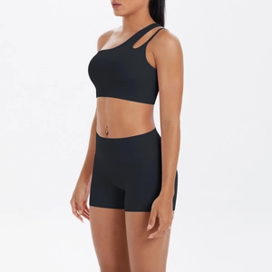 Detail of black one-shoulder yoga bra and high-waisted shorts set on model in studio