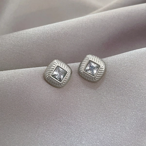 Macro detail of silver titanium steel earrings with square zircon and textured borders