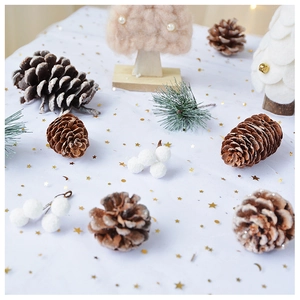 Flat lay of natural pine cones and white berries on sequined mesh for Christmas decor