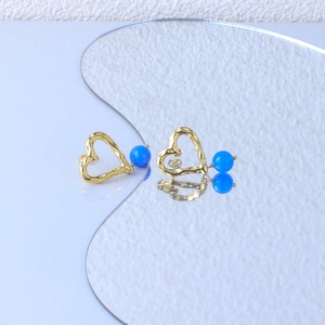 Macro detail of vintage gold heart earrings featuring blue beads and textured finish