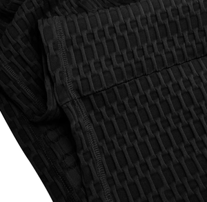 Vue macro du tissu noir à texture nid d'abeille sur un pantalon de yoga de sport