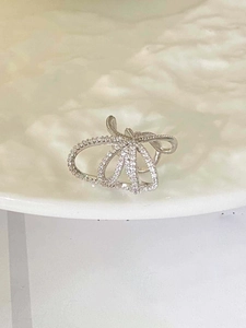 Detail view of silver multi-layer ear cuff with white zircon stones on textured surface