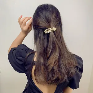 Elegant golden feather hair clip with rhinestone detail for stylish women's hairstyle