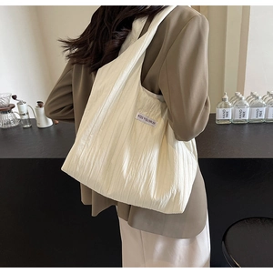Detail der weißen Nylon-Schultertasche mit Faltenstruktur und Kiss Yourself Etikett
