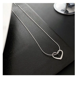 Close-up of polished silver heart pendant on a delicate snake chain necklace