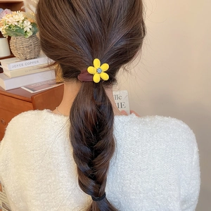 Détail d'un chouchou fleur jaune floqué avec strass porté sur une queue de cheval