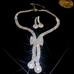 Macro shot of silver bow pendant necklace and matching diamond stud earrings on black background