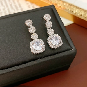 Detail of silver square earrings with zircon clusters on black jewelry box display