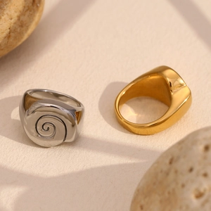Detailed view of spiral engraved sea shell patterns on 18K gold and silver steel rings