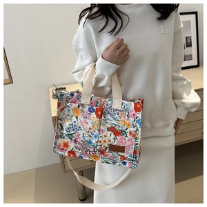 Close-up of floral canvas tote bag showing dual front pockets and leather fashion tag