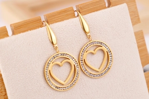Detail of gold dangle earrings with sparkling zircon halo and hollow heart design
