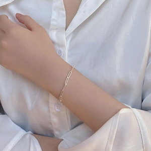 Close-up of a silver minimalist safety pin link chain bracelet on a woman's wrist