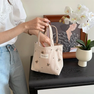 Detailed close-up of beige corduroy tote bag featuring cute embroidered bear patterns