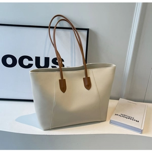 Minimalist beige tote bag with slim brown straps on white background with a book detail