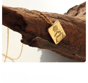 Macro detail of Egyptian sun pendant with zircon inlays and textured 18k gold plating