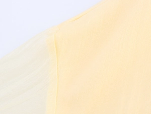 Vue détaillée de la texture du tissu en mousseline jaune clair et des coutures de la robe