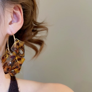 Close-up of leopard print petal C-shaped earrings on model ear with retro design