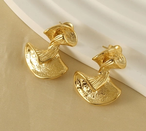 Detailed macro view of gold-tone irregular earrings with unique hammered metal texture