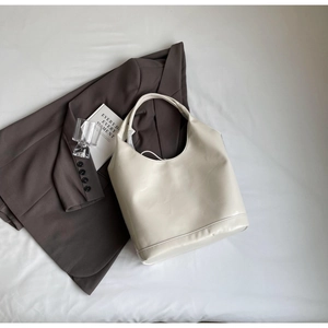 Close-up of beige faux leather hobo bag on a brown blazer for professional office styling