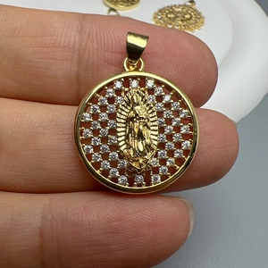 Gold Virgin Mary pendant with sparkling zircons held by hand showing fine details