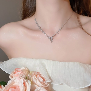 Close-up of sparkling zircon flower and bow pendant necklace worn on a woman neck
