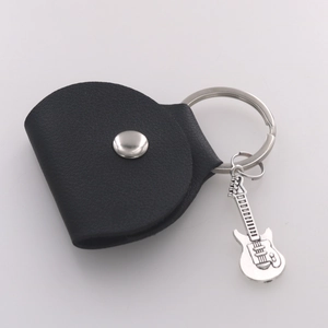 Detail of black leather guitar pick pouch with metal snap and guitar pendant keychain