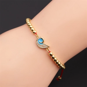 Close-up of gold beaded bracelet with blue enamel charm and micro-set zircons on wrist