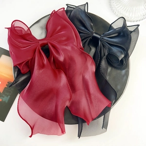 Detail of elegant oversized red and black organza bow hair clips on a minimalist tray