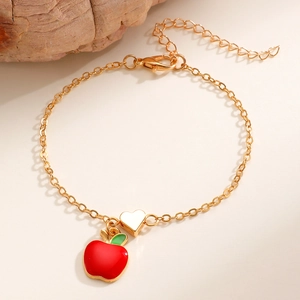 Dettaglio del bracciale a catena dorata con ciondolo a mela rossa e piccolo cuore