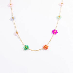 Macro shot of 18k gold plated necklace with colorful floral crystal charms on white