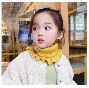 Detail of yellow knitted ruffles collar with pink plush doll on beige fleece coat