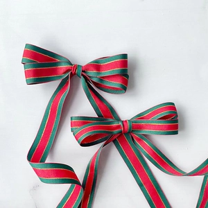 Classic red and green striped Christmas ribbon bows with gold accents on marble background