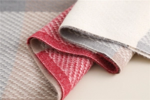 Close-up of soft plaid scarf fabric with red and beige wool texture and tassel detail
