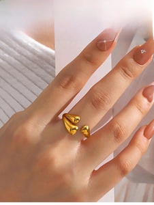 Detail of gold water drop ring worn on hand with a polished mirror finish on white knit
