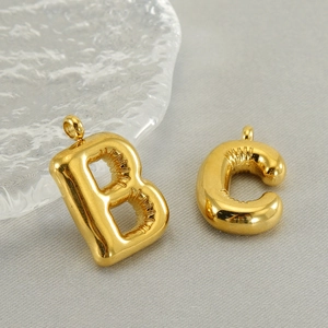 Macro detail of gold bubble letters B and C with 3D polished finish on a glass plate